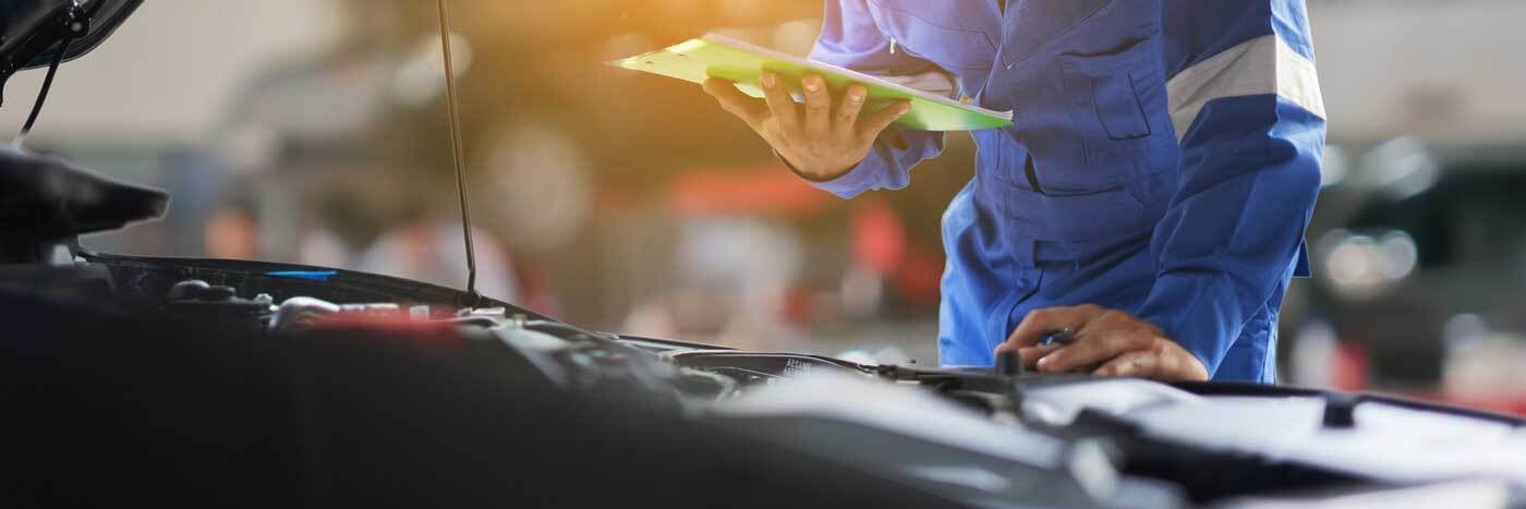 View of a service tech inspecting a vehicle's engine